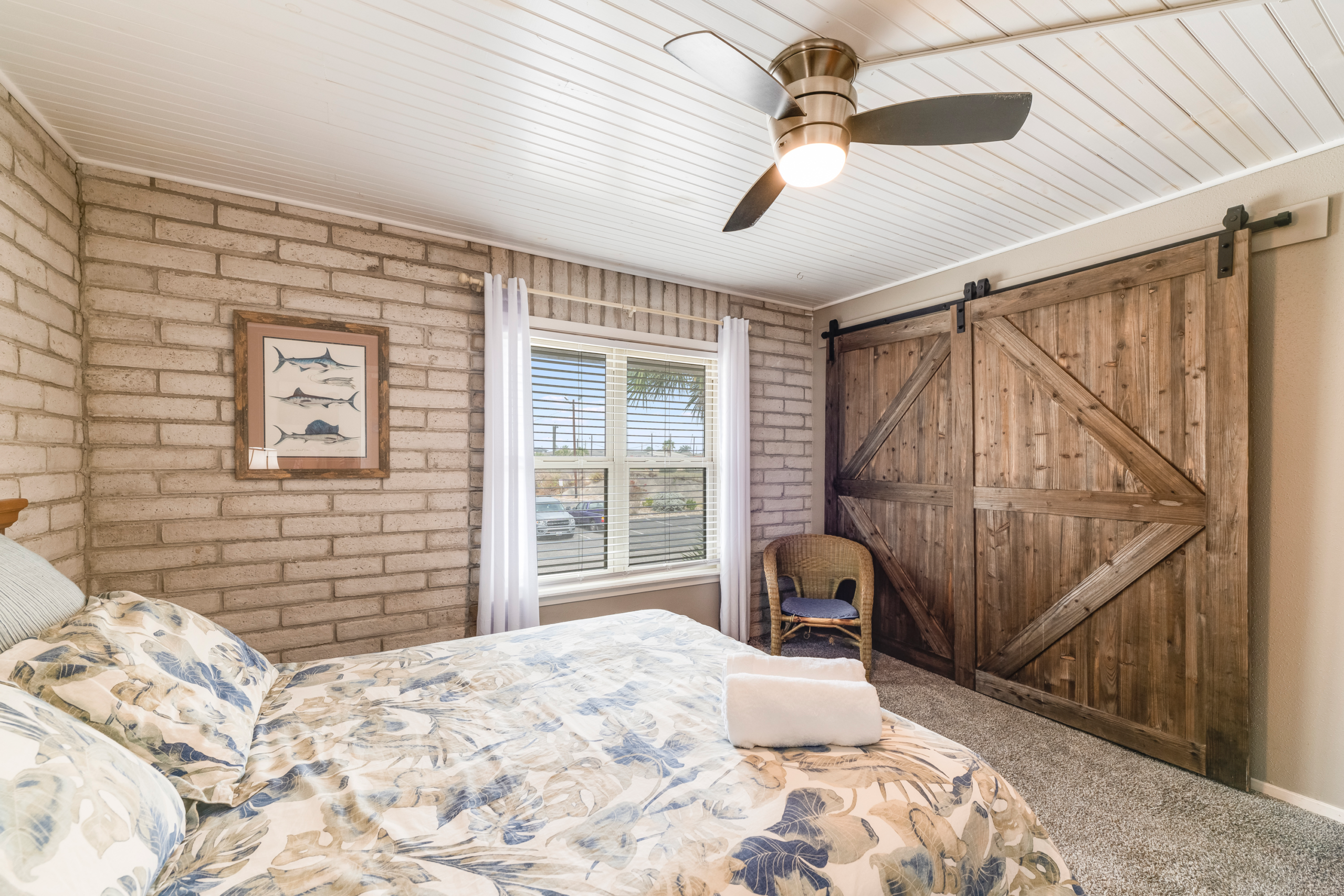 Main-level queen bedroom with brick walls and coastal decor in Port Aransas condo for groups up to 10