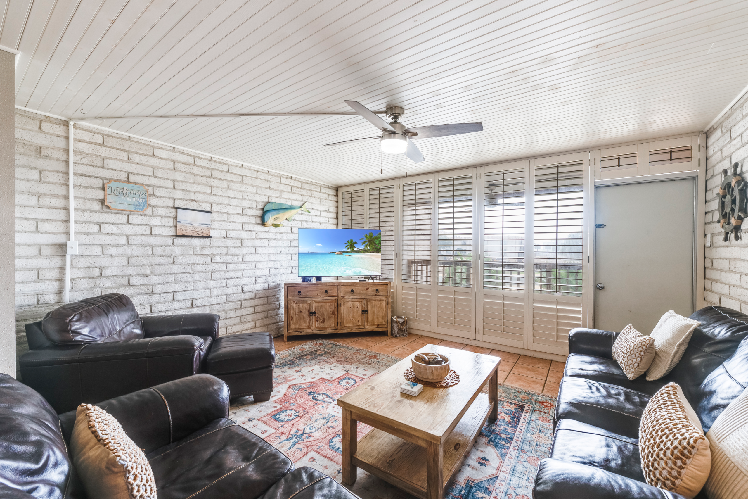 Spacious living and dining area with leather seating and brick walls in Port Aransas condo