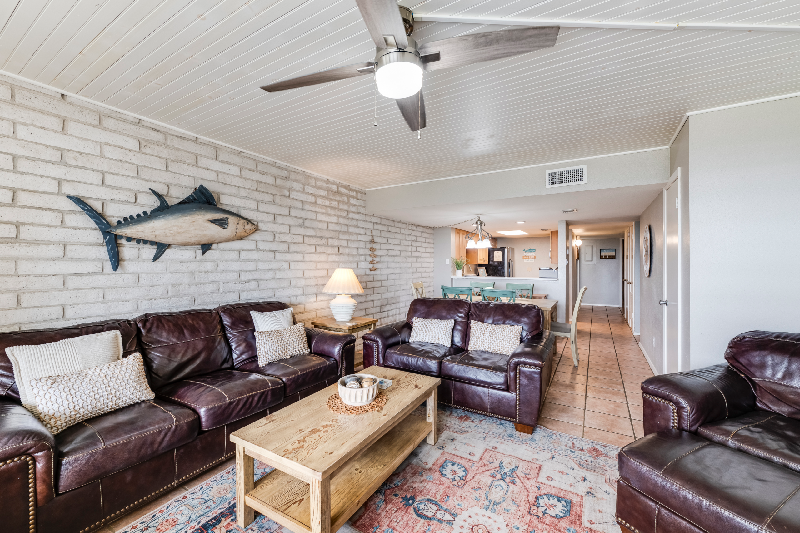 Spacious living and dining area with leather seating and brick walls in Port Aransas condo